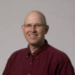 A bald man wearing glasses and a red shirt