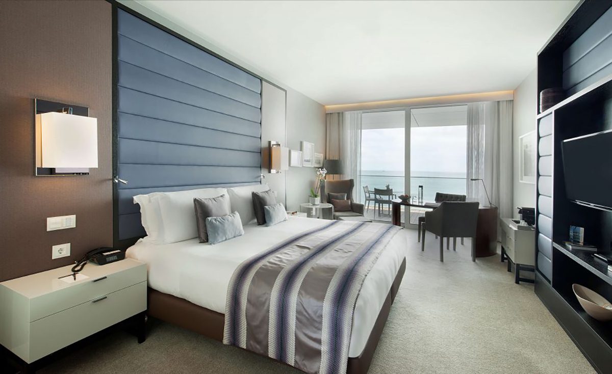 A bedroom with a grey throw and cushions