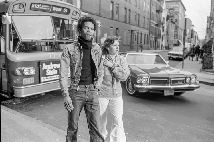 a black and white photo of a man and women walking in the street in New York