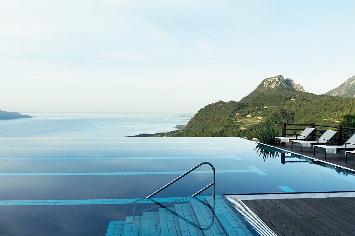 An infinity pool overlooking a lake and green mountain