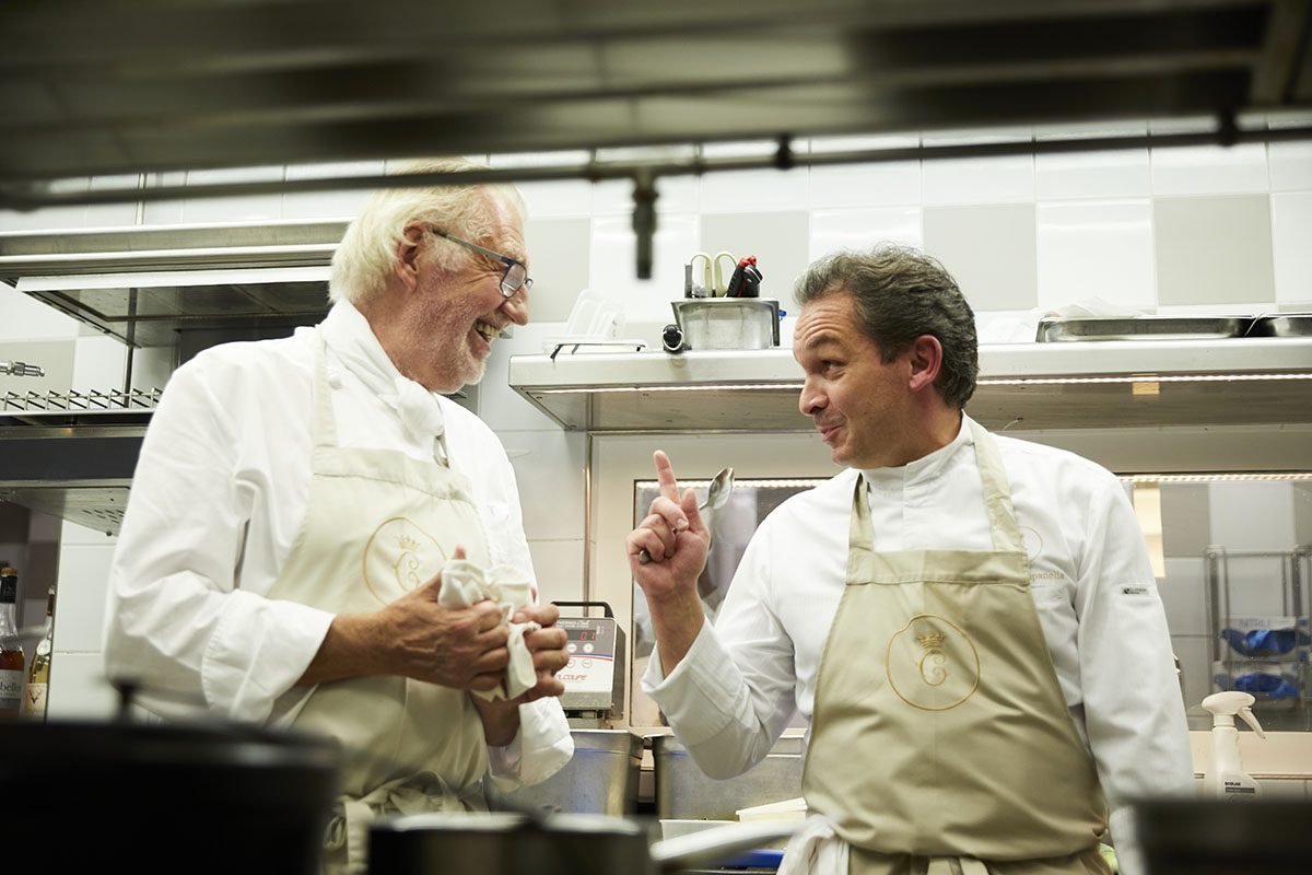 two chefs working in a kitchen with beige aprons
