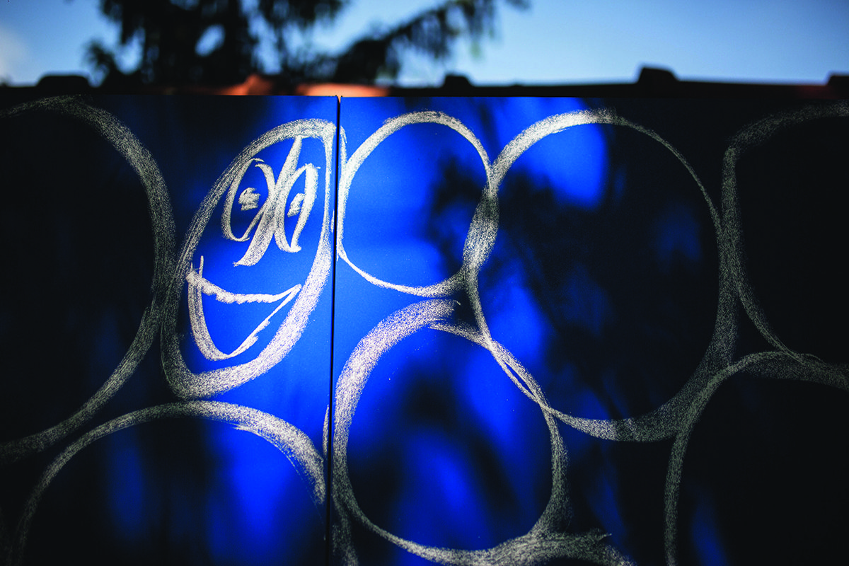 A smiley face drawn in white chalk on a blue panel