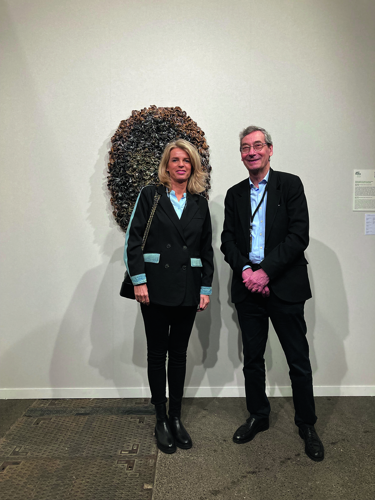 A woman and man standing in front of a piece of art on the wall