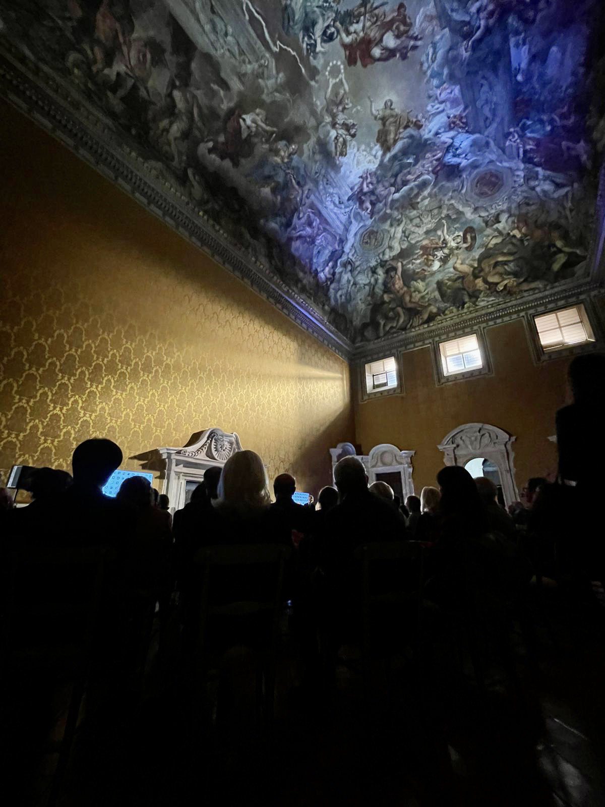 people standing in a room with yellow wallpaper and a painted ceiling