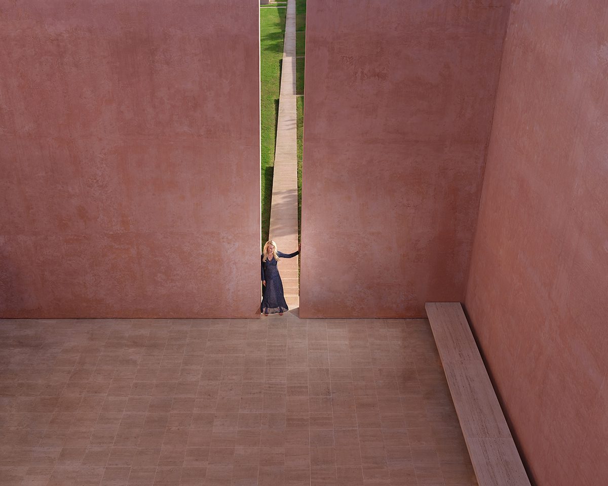 A woman leaning against two large pink walls