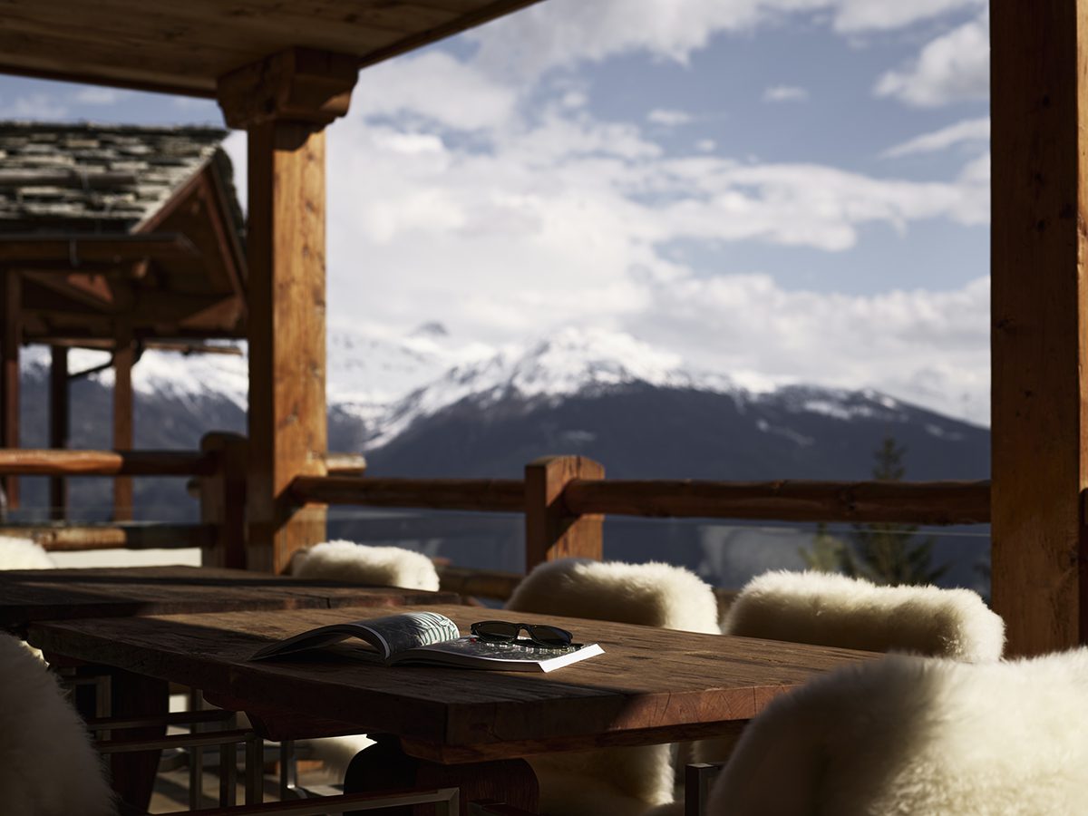 A terrace with a mountain view and sunglasses and a book on the table