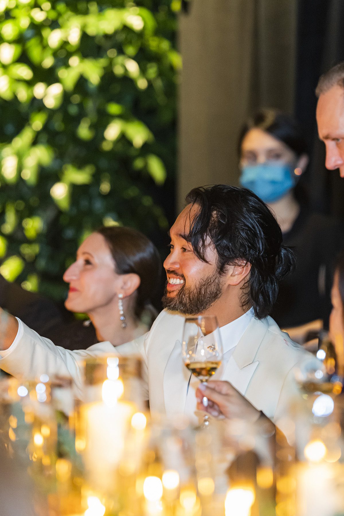 a man in a white shirt lifting his glass at a dinner
