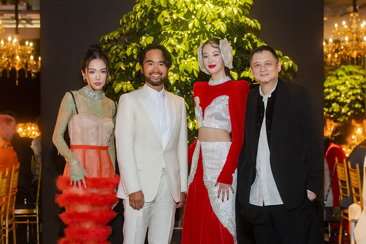 women in white ad red sparkly outfits and a man wearing a white suit with another in a black jacket and white t shirt