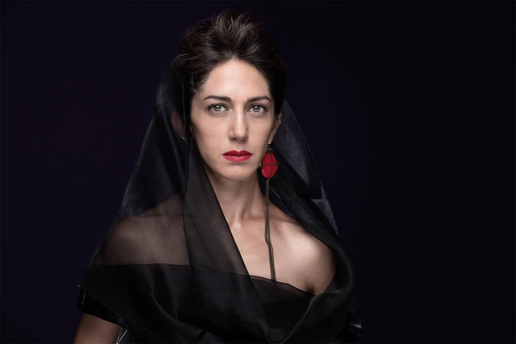 A woman wearing a black veil and dress and red earrings