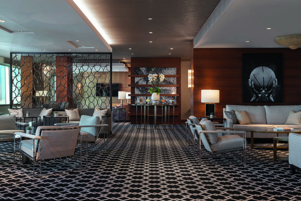 A lounge with a patterned carpet and cream chairs