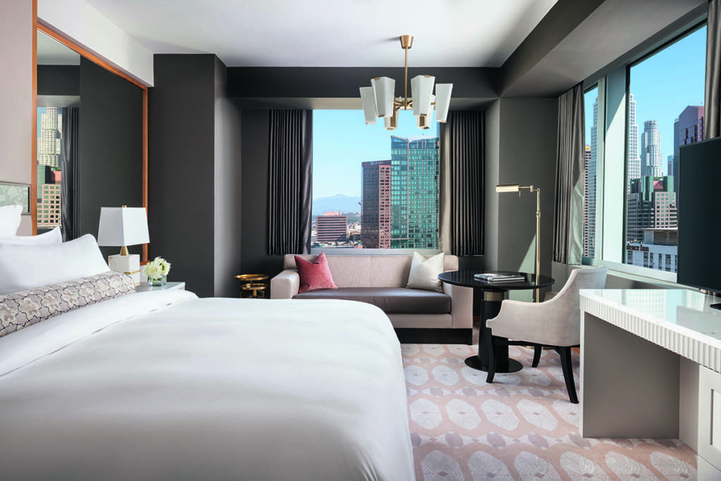 A bedroom with windows overlooking a city