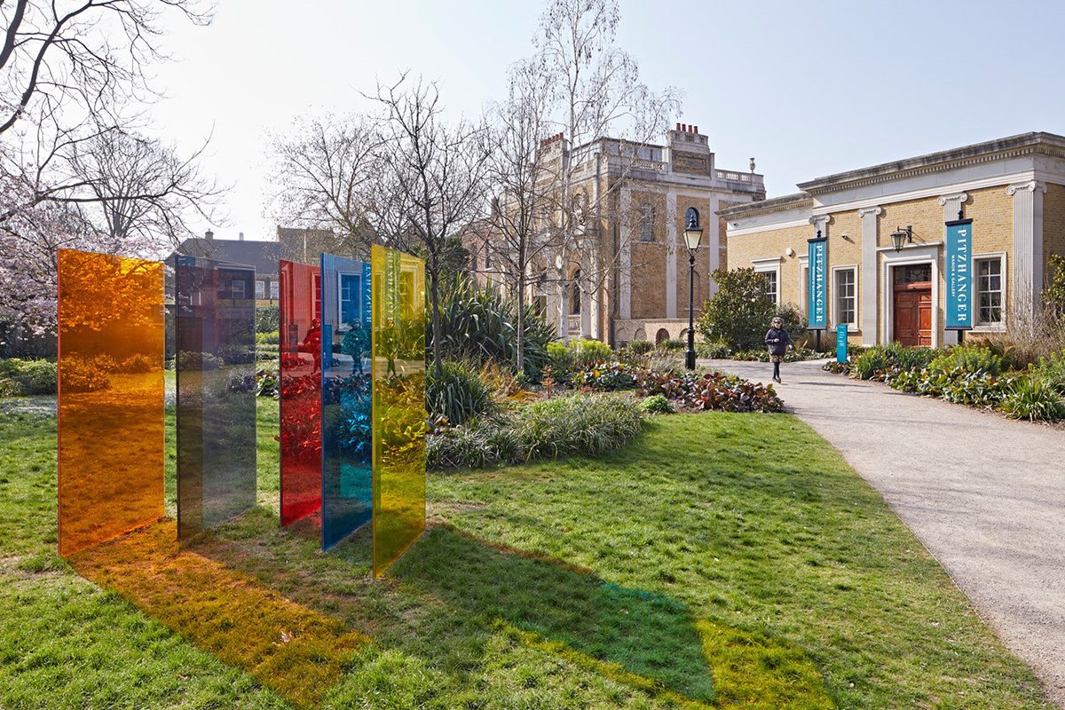 red, blue, yellow and green glass frames on grass outside a building