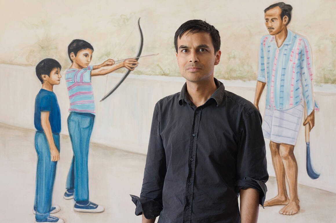 A man standing in front of a painting of a boy with a bow and arrow