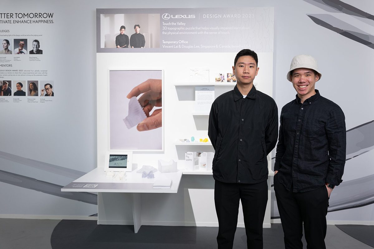 Two men standing next to a screen showing a presentation