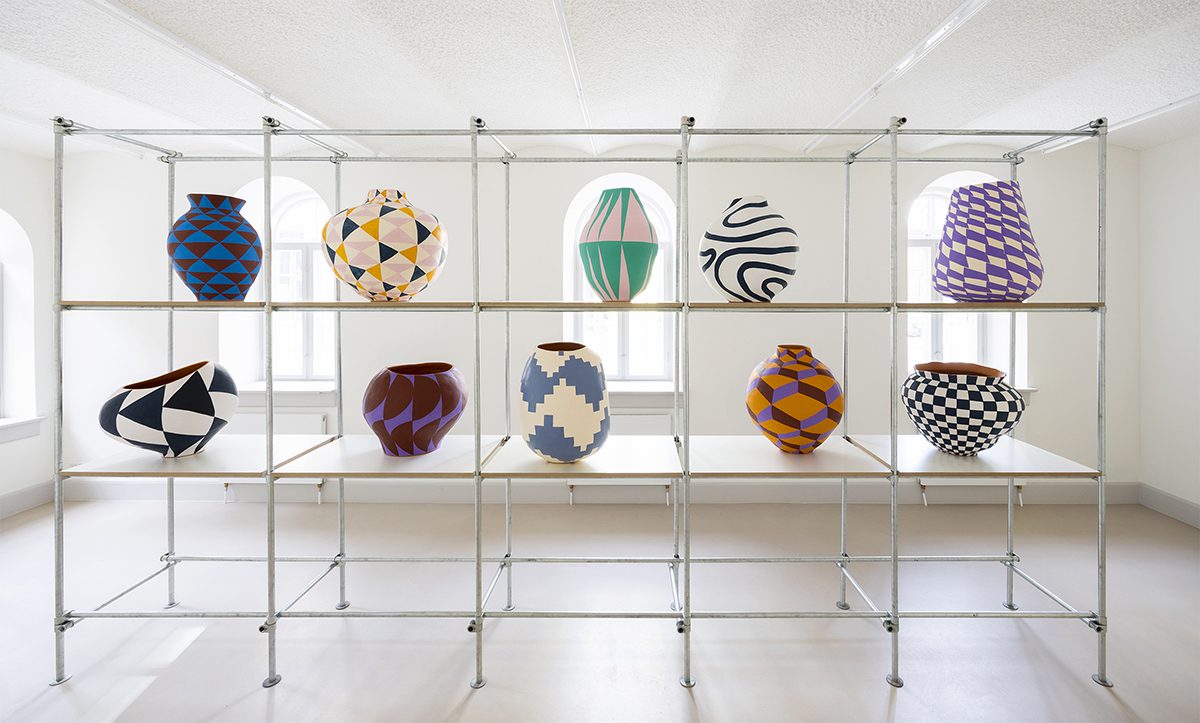 colourful vases on a shelf in the middle of a room