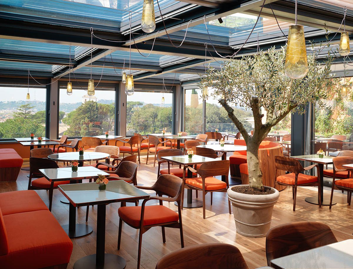 A restaurant with a tree in the middle and red cushioned chairs