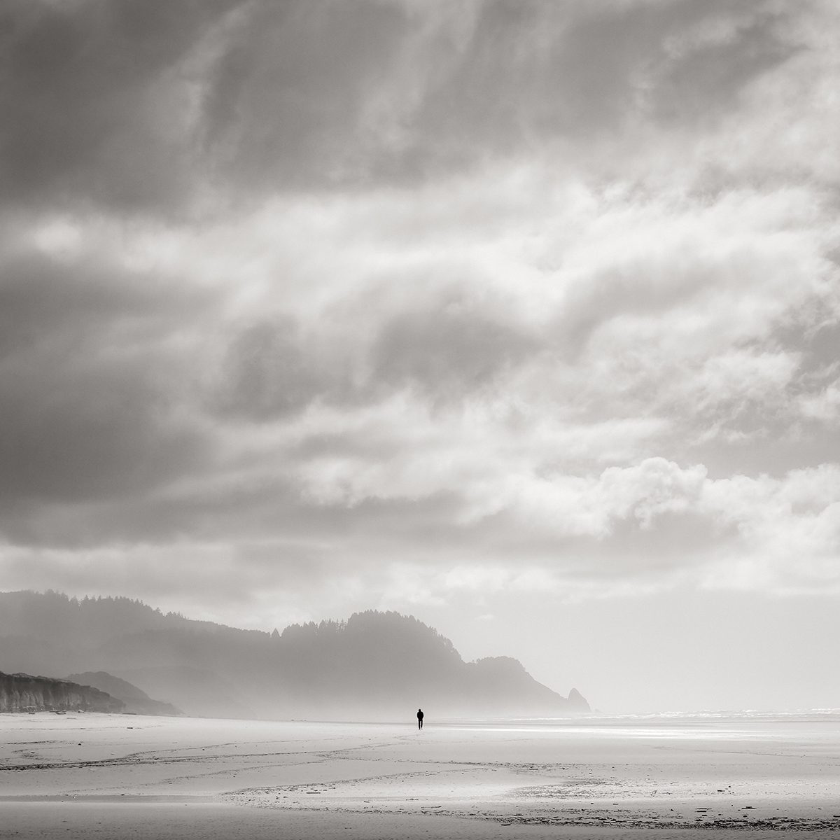 grey sky and a beach with a mountain in the distance