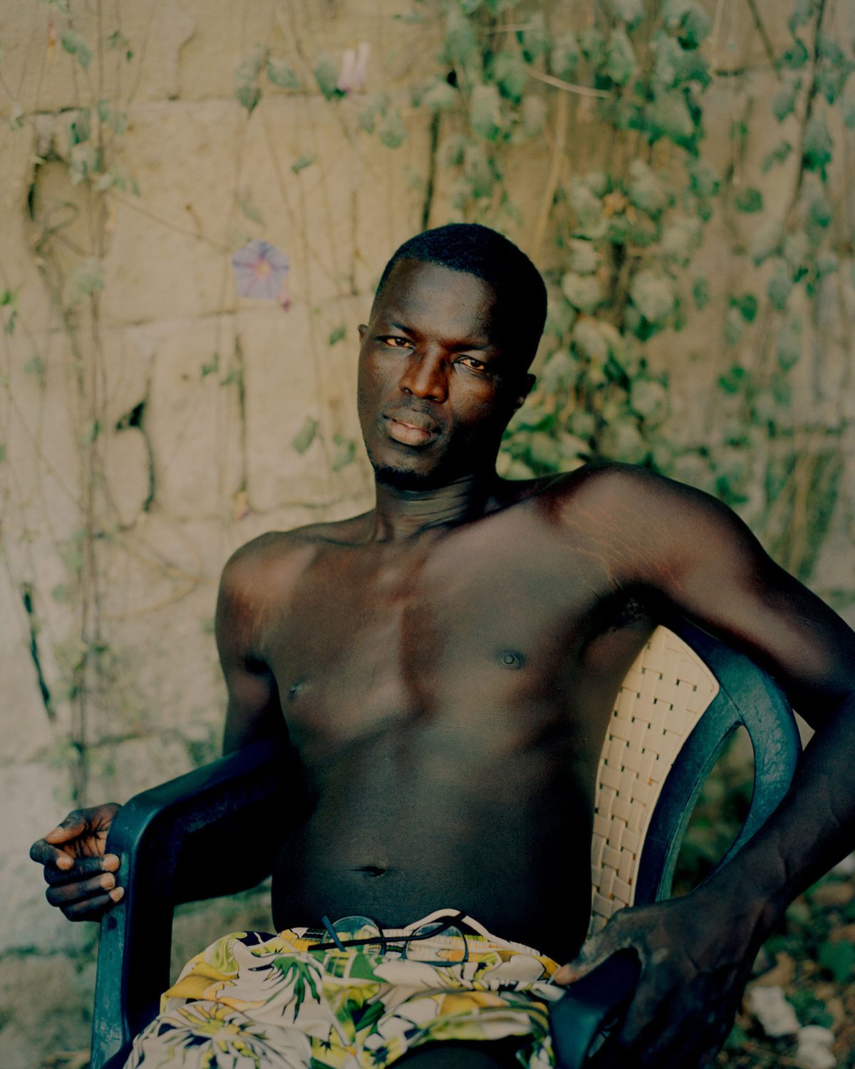 A man lounging on a chair topless