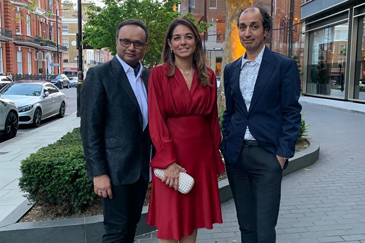 two men standing next to a woman wearing a red dress