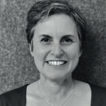 A woman with short short hair wearing a necklace and t-shirt 