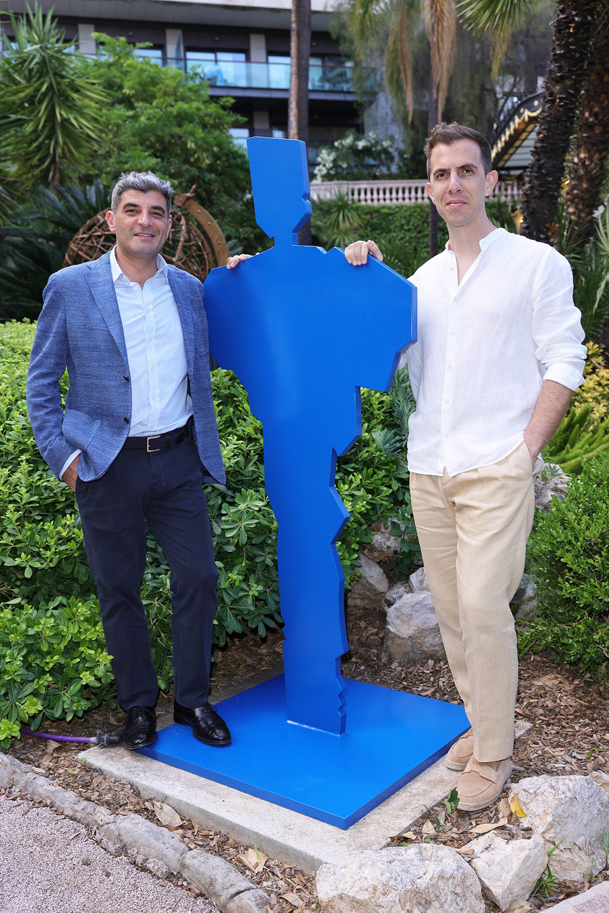 Two men standing next to a blue statue of a person