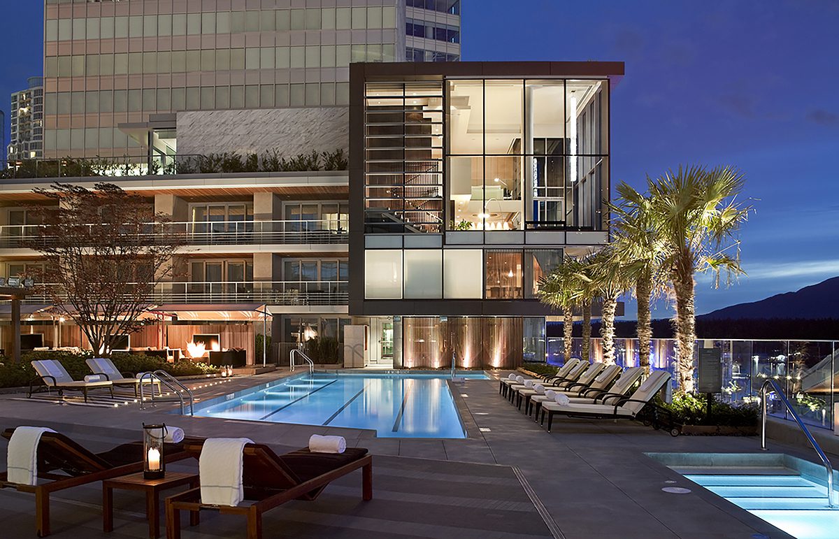A pool outside a lit up building at night
