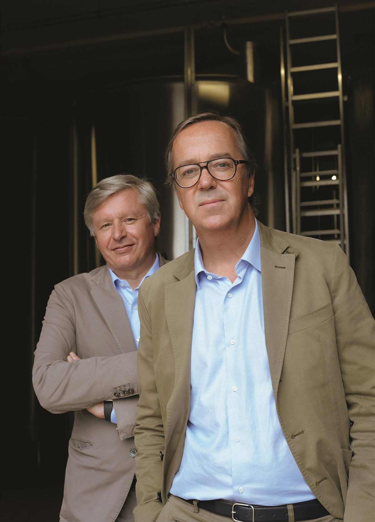 Two men wearing brown jackets and shirts