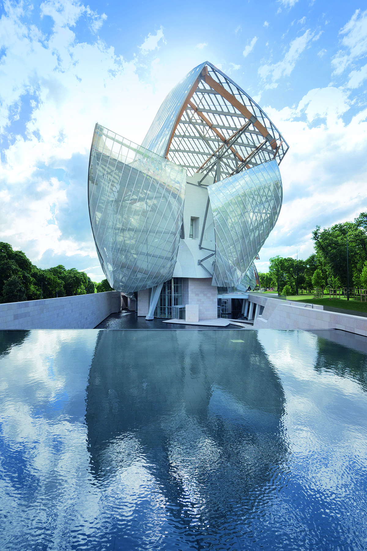 A warped shaped glass building with a pool in front of it 