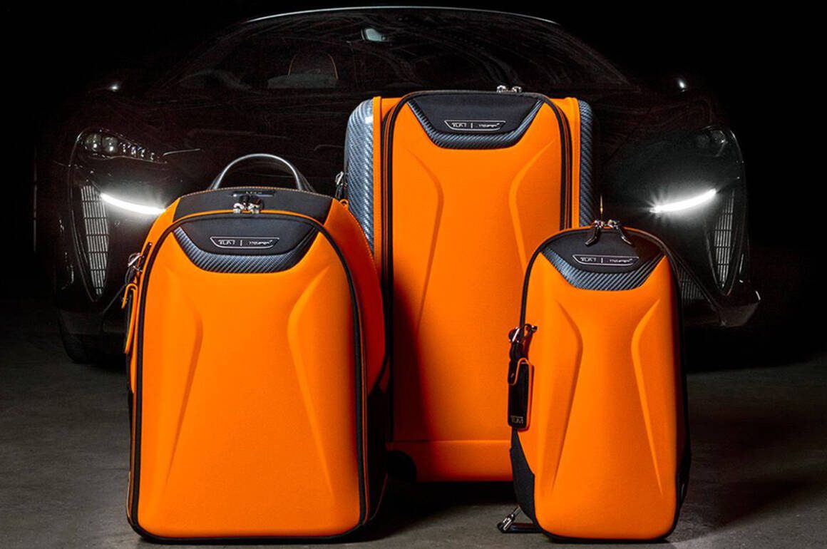orange suitcases and rucksack in front of a black sportscar