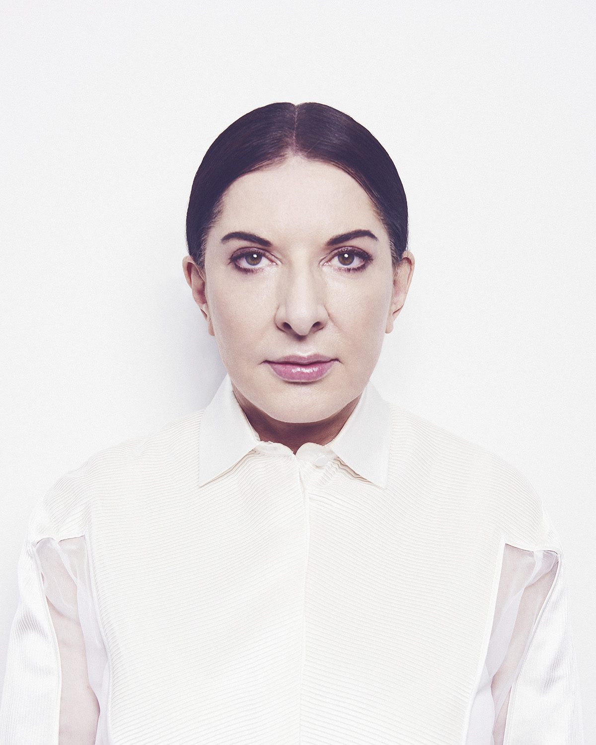 A woman with her hair back wearing a white shirt