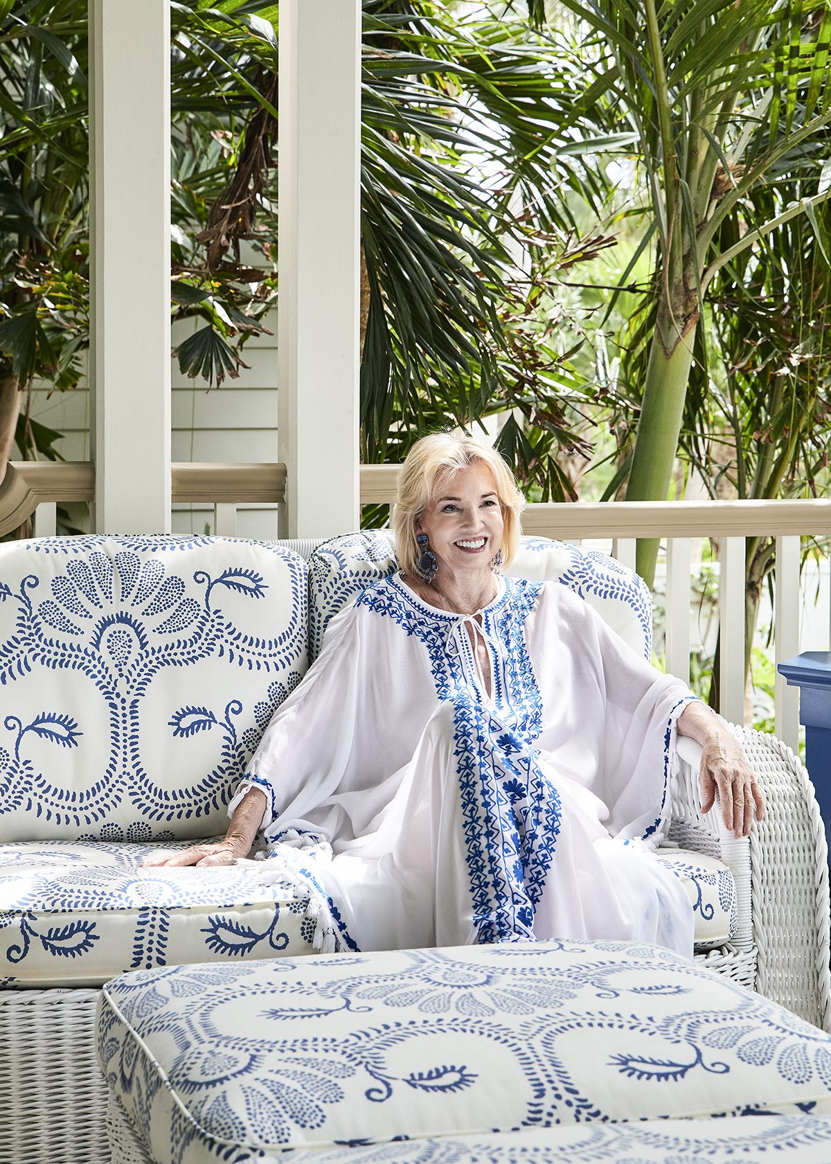A woman wearing a white and blue dress sitting on a blue and white sofa