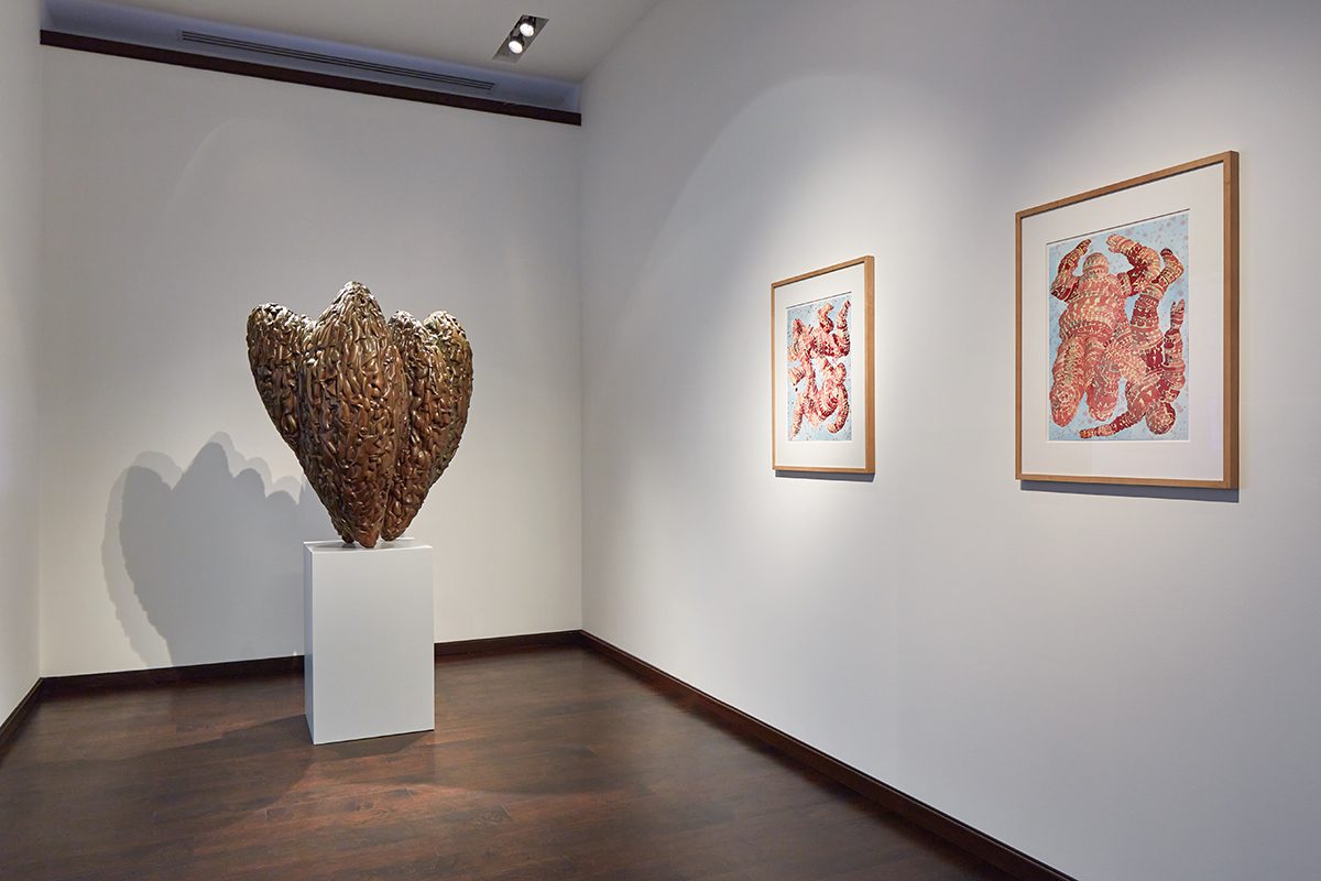 A sculpture beside red paintings