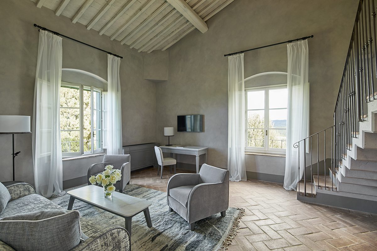 A beige bedroom with white curtains around windows
