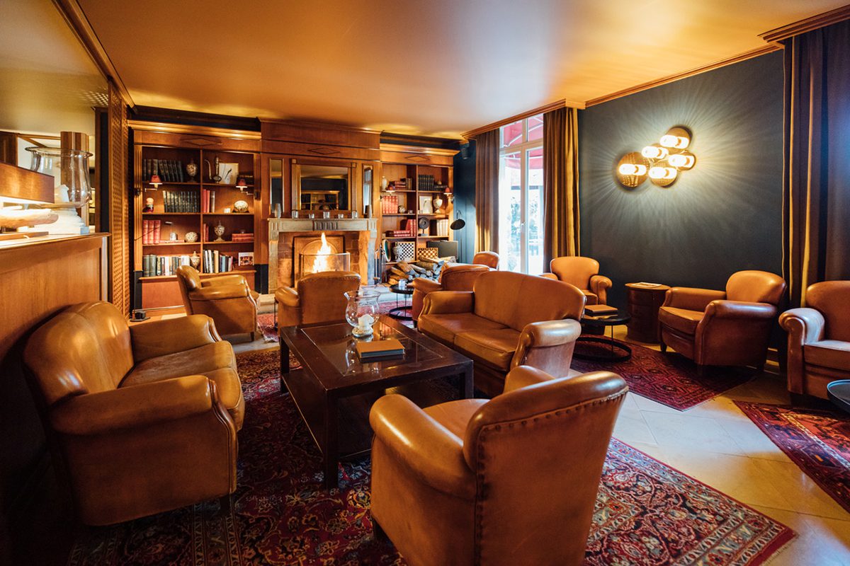A lounge with a fireplace and leather brown chairs