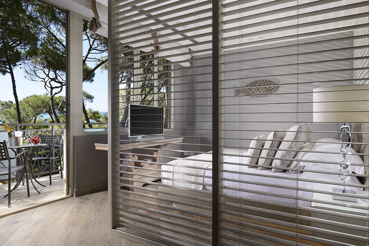 A wooden divider next to a bed looking out to trees