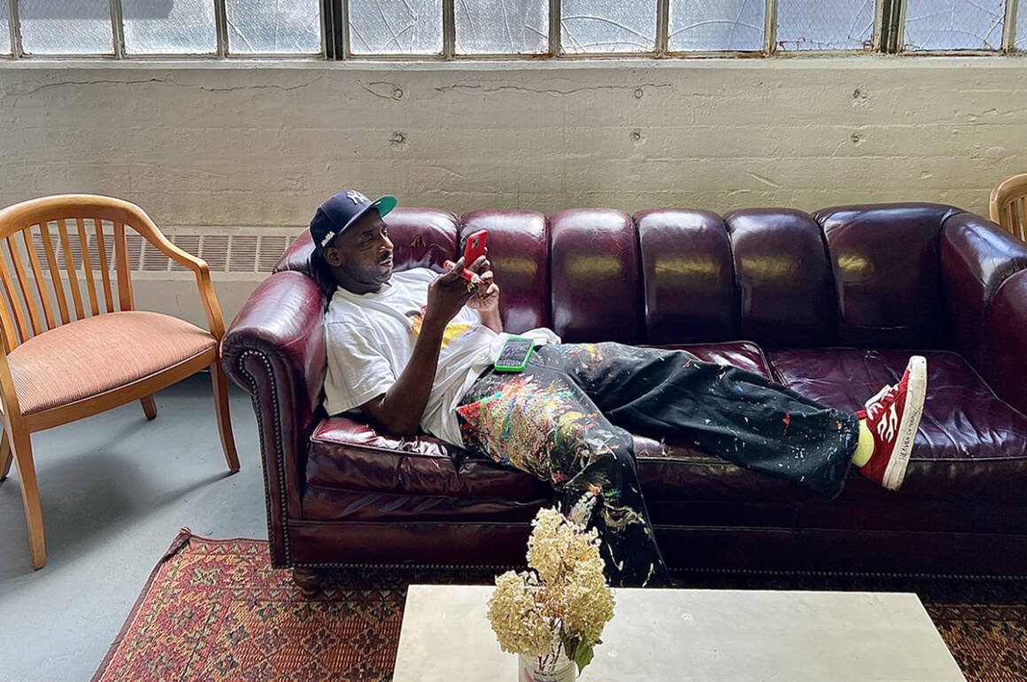 A man with paint on his jeans lying on a purple couch
