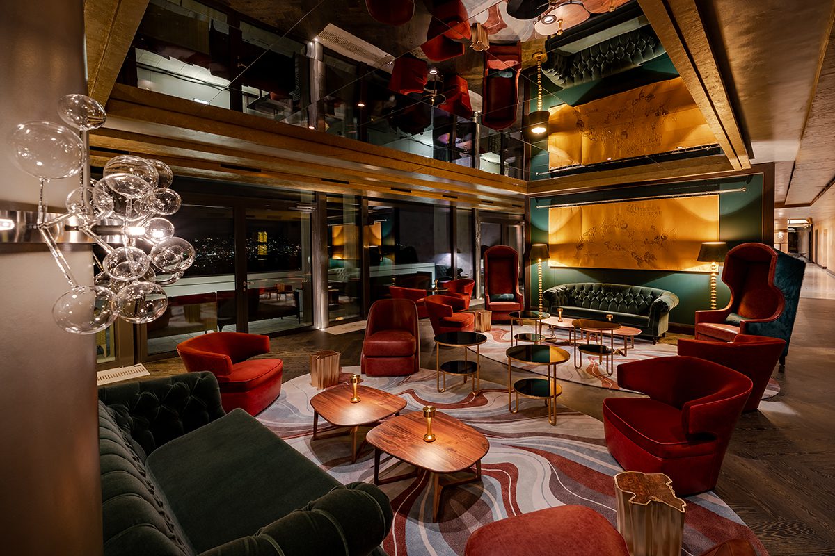 A lounge with green and red chars and dim lighting 