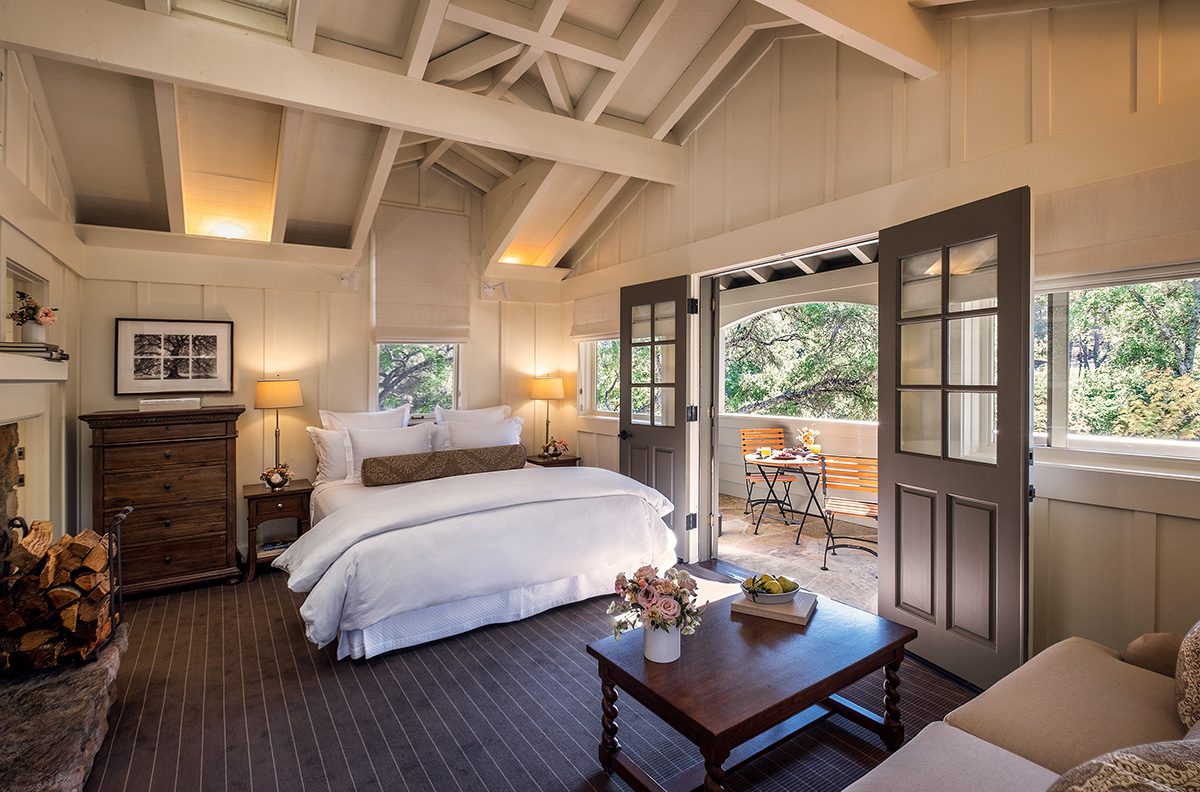 A white wooden bedroom with a white bed and dark brown wooden doors and floors