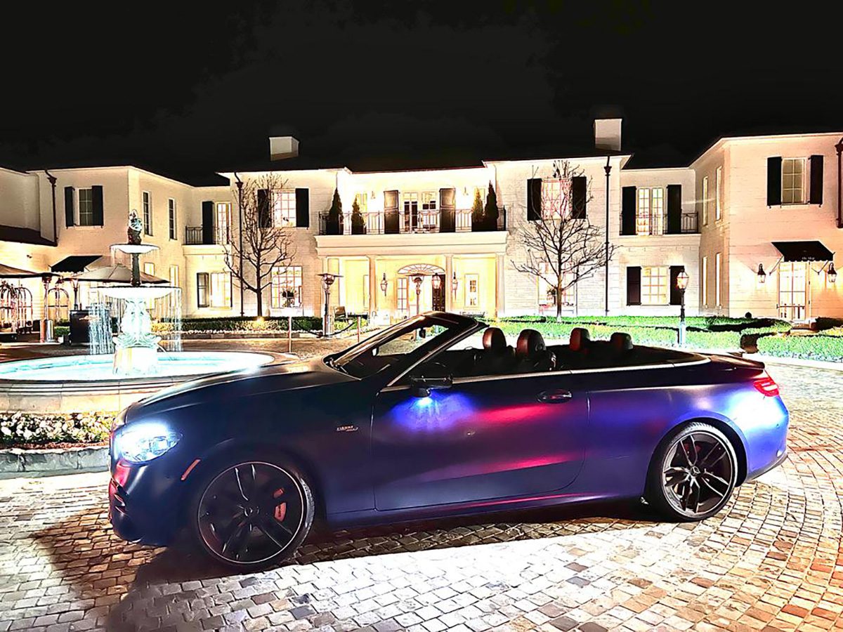 A blue lit up car parked outside a lit up grand hotel