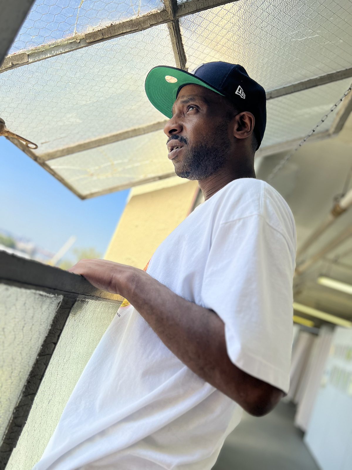 A man wearing a white t shirt and black and green cap