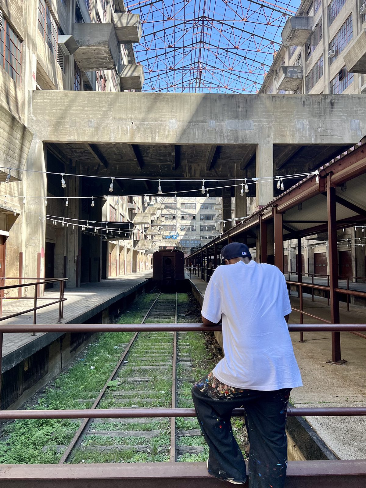 A man leaning over a bridge overlooking train tracks in a tunnel