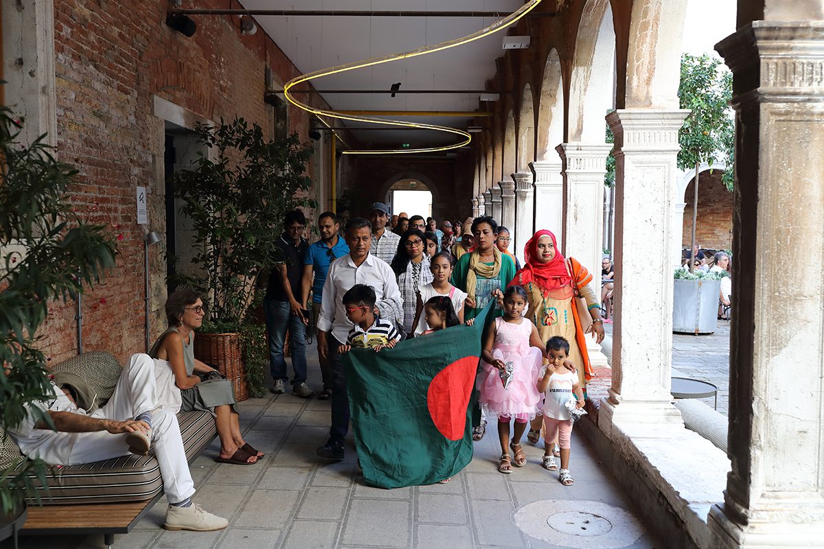 A group of people standing by some pillars holding a flag