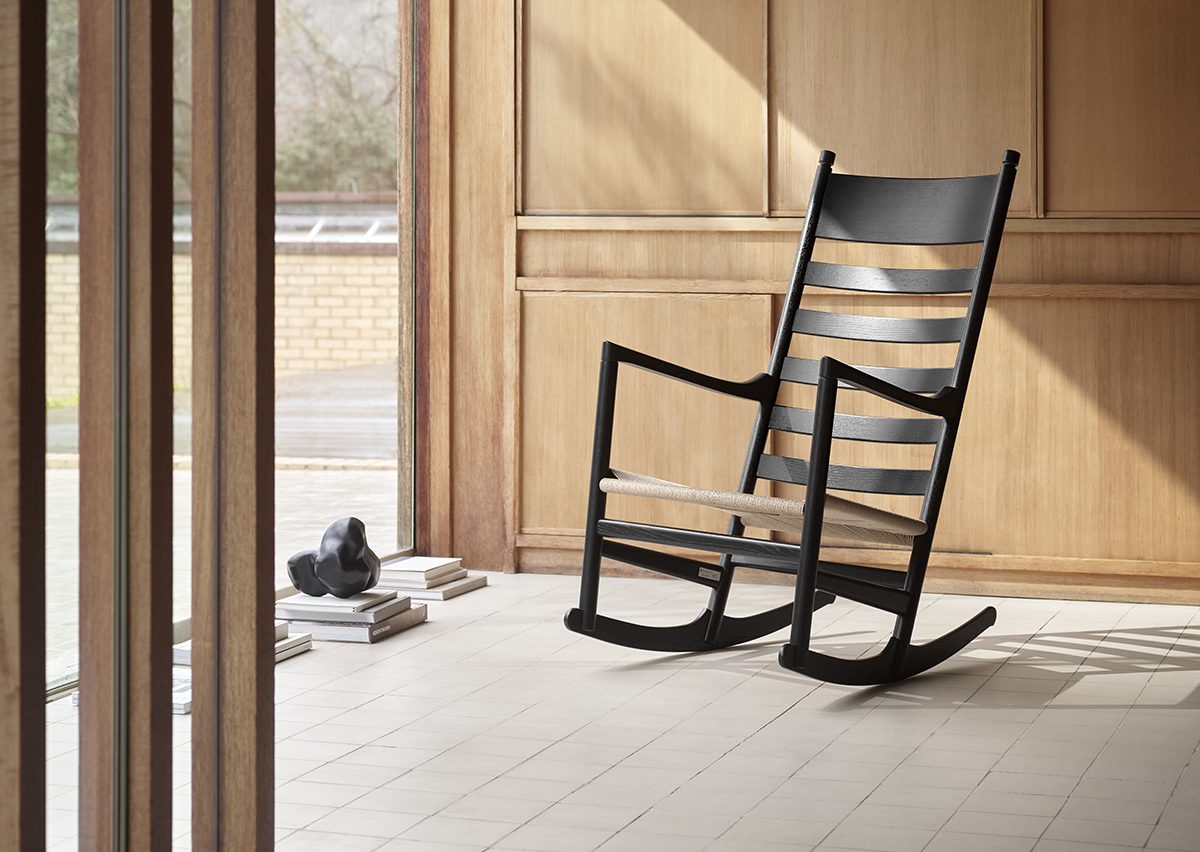 Black rocking chair next to wooden beams in the morning sun