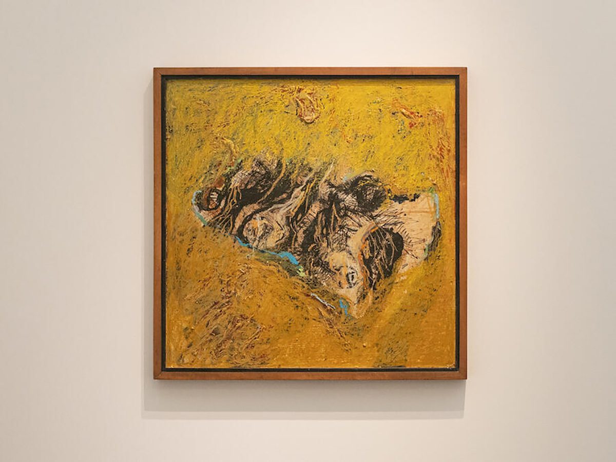 A gold painting with a black and beige drawing in the centre on a canvas hung on a wall