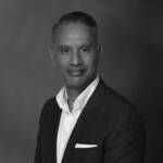 A man wearing a white shirt, pocket handkerchief and a grey suit