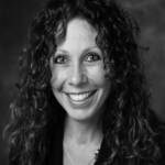 A woman with curly hair smiling wearing a black top