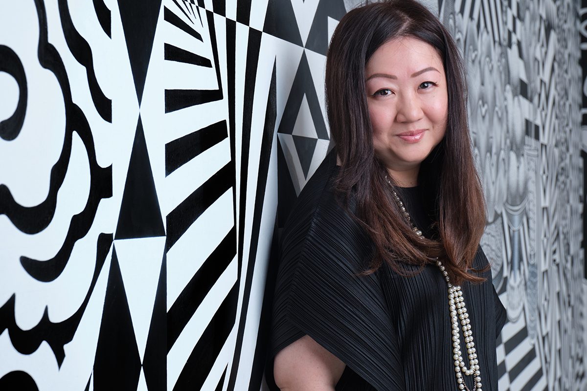 A woman wearing a black top standing next to a white and black wall