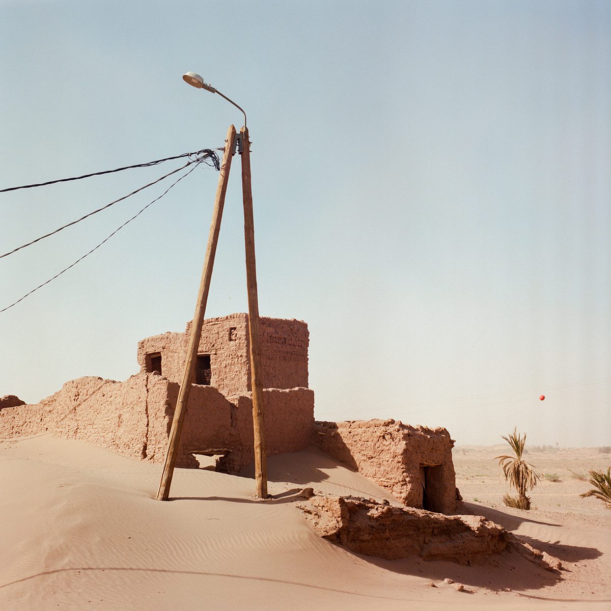 Stone building in the sand by a power line cop