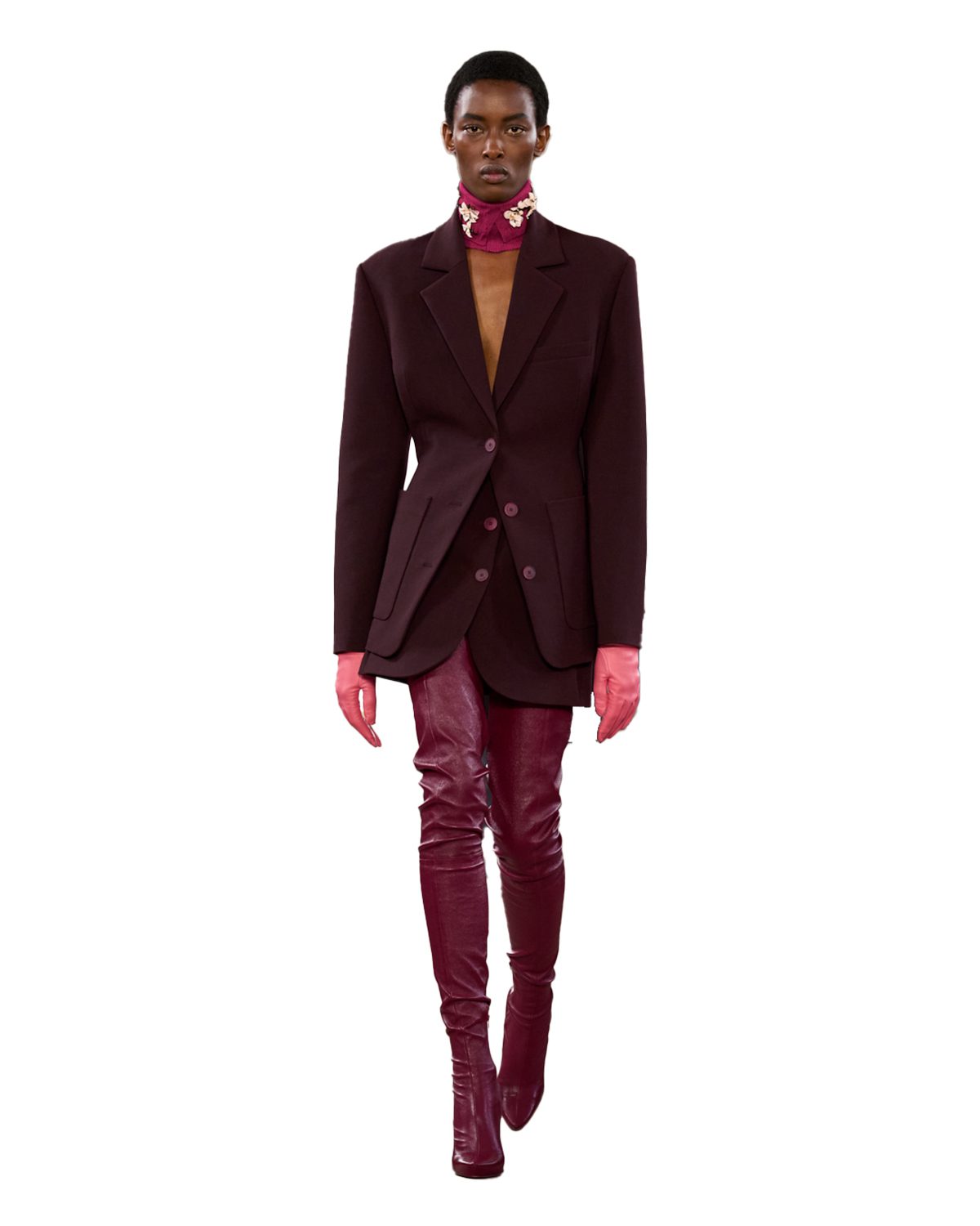 A woman wearing a brown blazer, burgundy skirt and boots