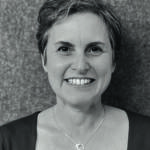 a woman with short hair wearing a necklace and smiling
